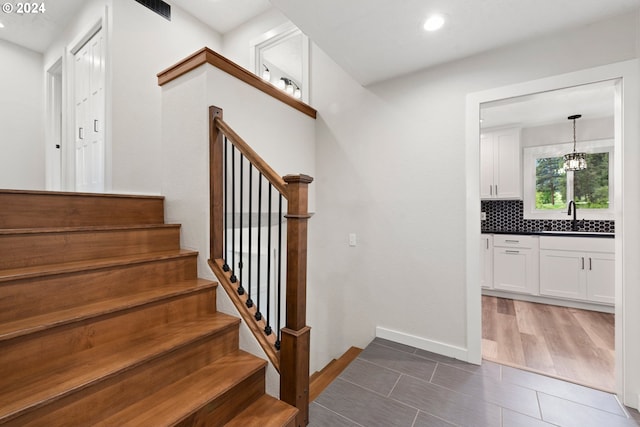 staircase featuring tile patterned floors and sink