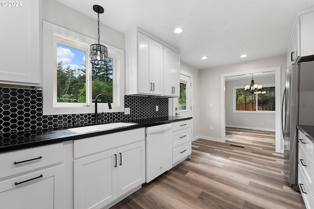 kitchen with white cabinetry, sink, an inviting chandelier, stainless steel fridge, and white dishwasher