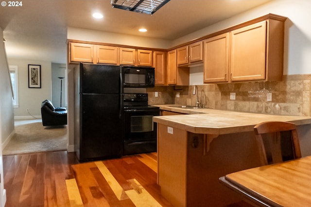 kitchen with tasteful backsplash, black appliances, dark hardwood / wood-style flooring, and sink