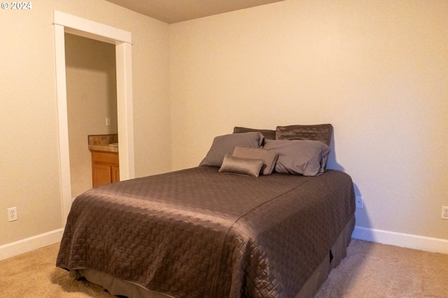 bedroom featuring light colored carpet and ensuite bathroom