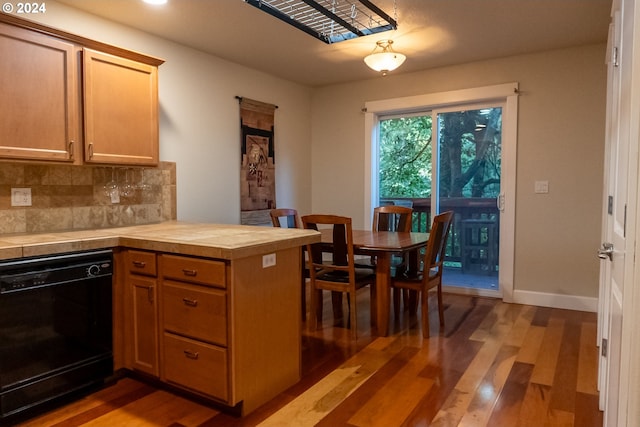 kitchen featuring wood-type flooring, dishwasher, backsplash, and tile counters