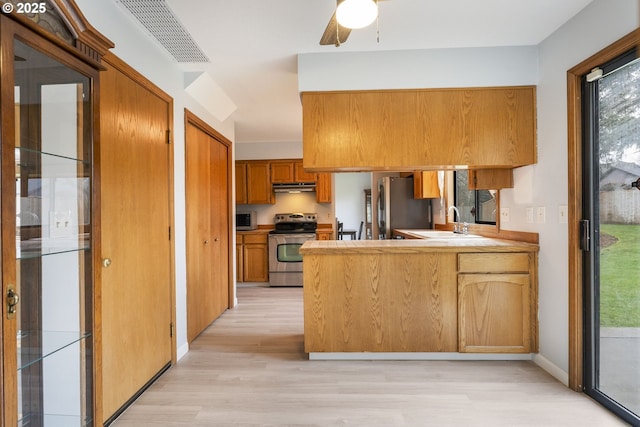 kitchen with sink, kitchen peninsula, ceiling fan, stainless steel appliances, and light hardwood / wood-style floors