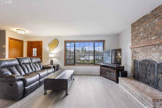 living room featuring a brick fireplace and light wood-type flooring