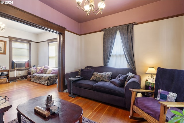 living room with cooling unit, an inviting chandelier, and hardwood / wood-style floors