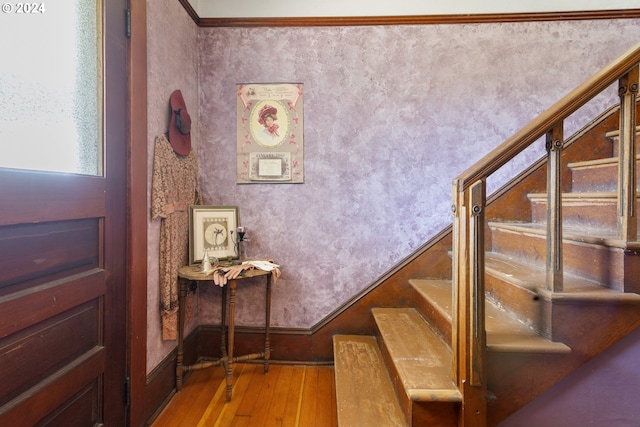 stairs featuring crown molding and hardwood / wood-style floors