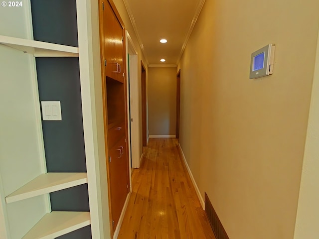 hallway with ornamental molding and light hardwood / wood-style floors