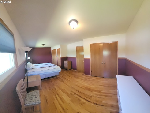 bedroom with multiple closets and light hardwood / wood-style floors