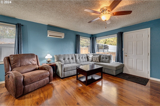 living room featuring wood-type flooring, a textured ceiling, an AC wall unit, and ceiling fan