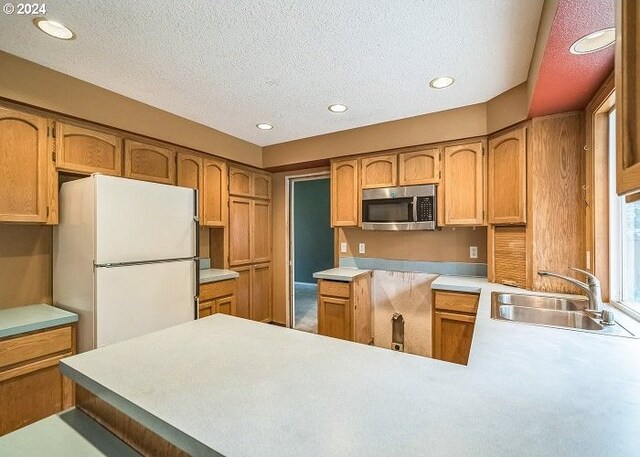 kitchen featuring a textured ceiling, sink, white refrigerator, and kitchen peninsula