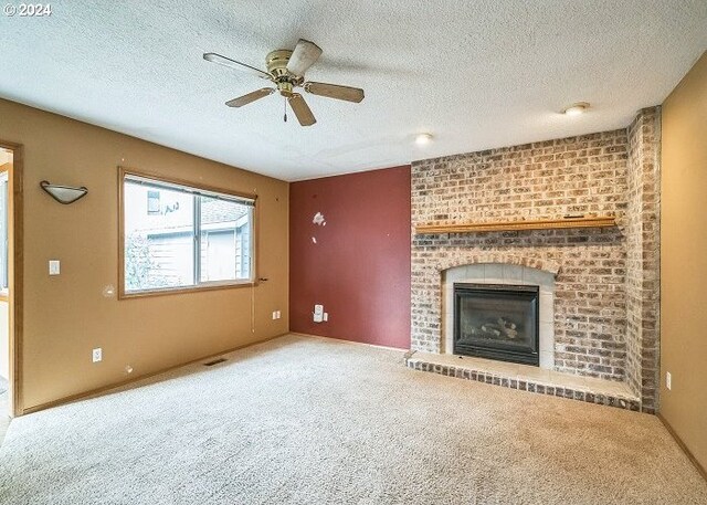 unfurnished living room featuring a textured ceiling, carpet flooring, ceiling fan, and a fireplace