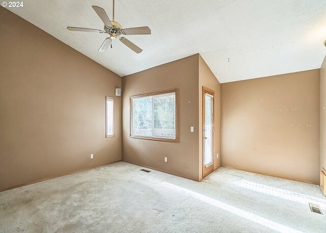 spare room with light colored carpet, ceiling fan, and vaulted ceiling