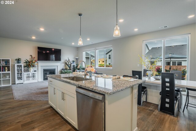 kitchen featuring an island with sink, light stone counters, sink, white cabinetry, and dishwasher