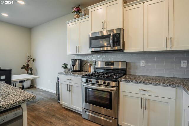 kitchen with white cabinets, appliances with stainless steel finishes, dark hardwood / wood-style flooring, and stone countertops