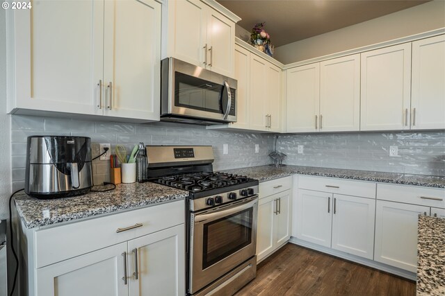 kitchen featuring stainless steel appliances, light stone countertops, white cabinets, and dark hardwood / wood-style flooring