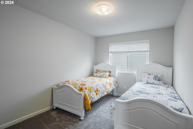 bedroom featuring dark colored carpet and a textured ceiling