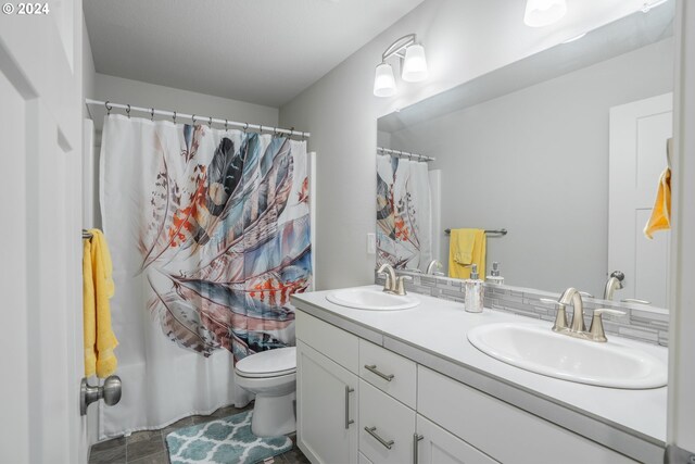 bathroom featuring tile patterned flooring, curtained shower, vanity, and toilet