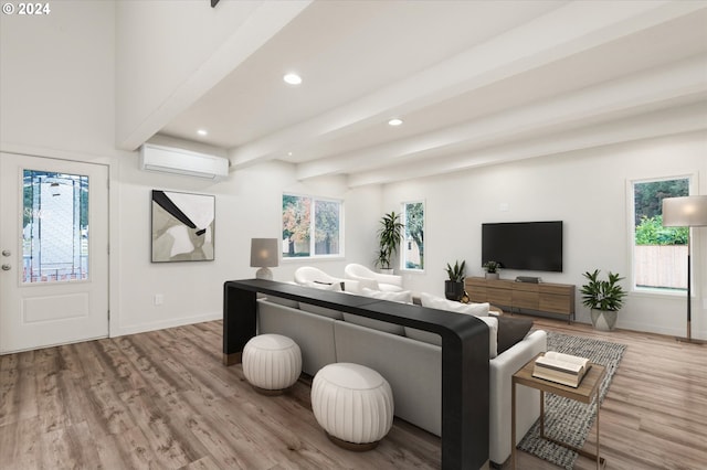 living room with beam ceiling, light wood-type flooring, and a wall unit AC