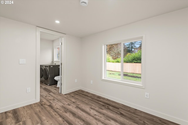 spare room with independent washer and dryer and hardwood / wood-style flooring