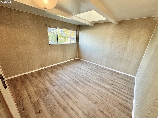 unfurnished room featuring wood finished floors, beam ceiling, and wooden walls