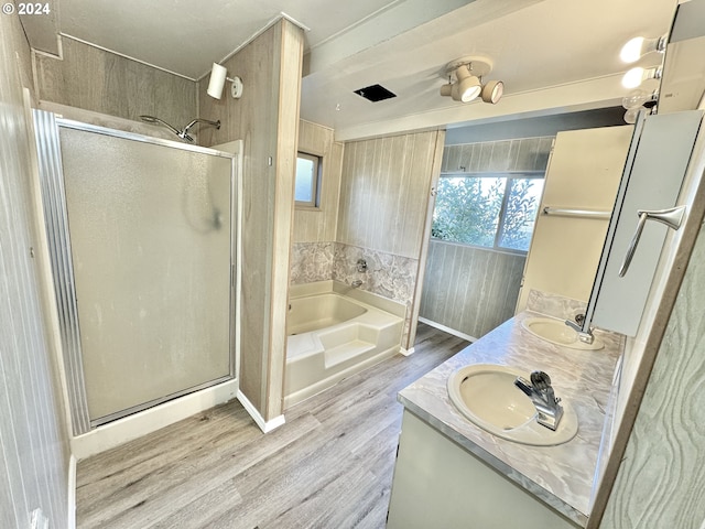 bathroom featuring wood finished floors, a stall shower, a garden tub, and double vanity