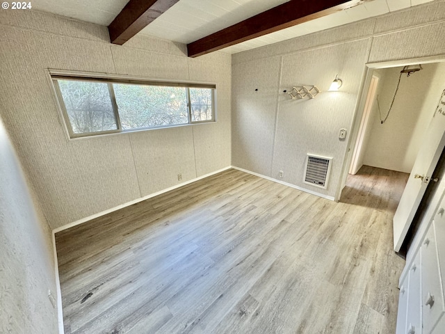 spare room with light hardwood / wood-style floors, beamed ceiling, and heating unit