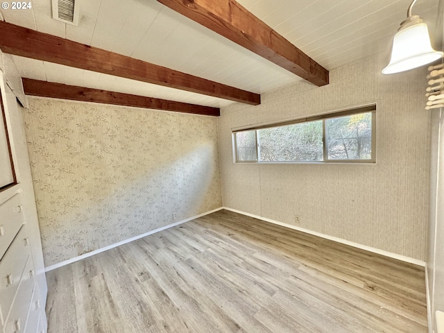unfurnished room with wood finished floors, beam ceiling, wallpapered walls, and baseboards