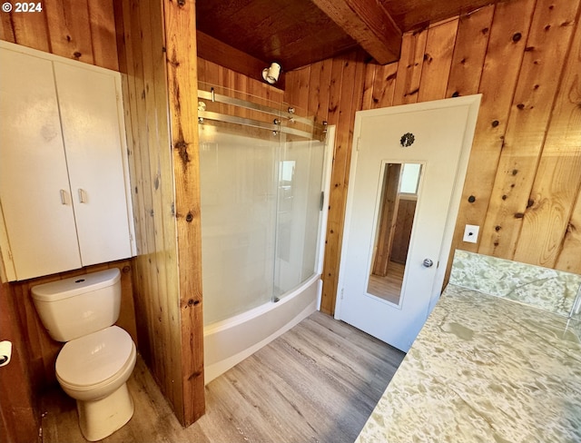 full bathroom with beamed ceiling, wood-type flooring, wooden walls, and toilet