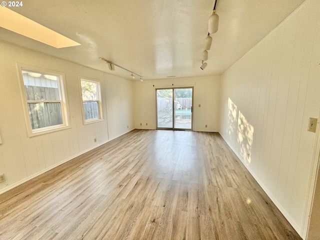 unfurnished room featuring light hardwood / wood-style flooring, a skylight, and rail lighting