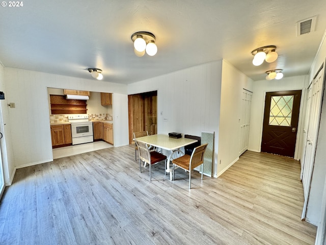 dining room with light wood finished floors, baseboards, and wooden walls