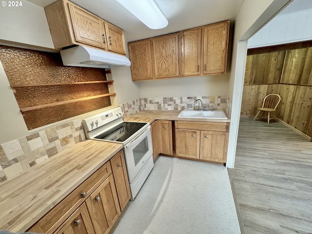 kitchen with white electric range oven, wood counters, wood walls, decorative backsplash, and sink