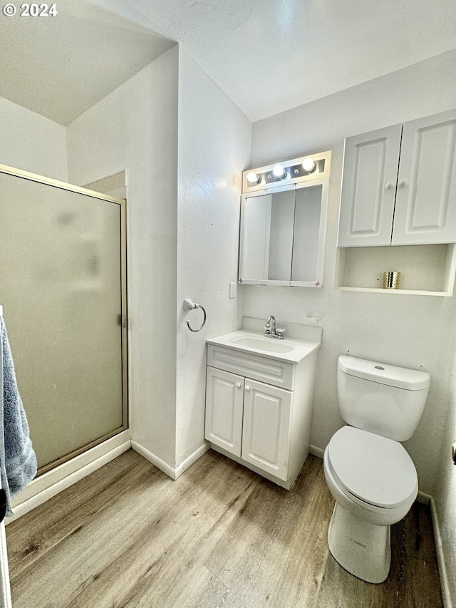 bathroom with wood finished floors, baseboards, a shower stall, and vanity