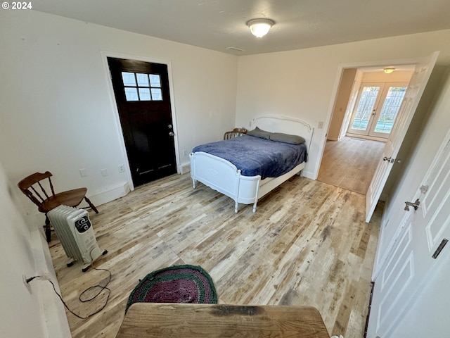 bedroom featuring light wood-style flooring, multiple windows, french doors, and baseboards