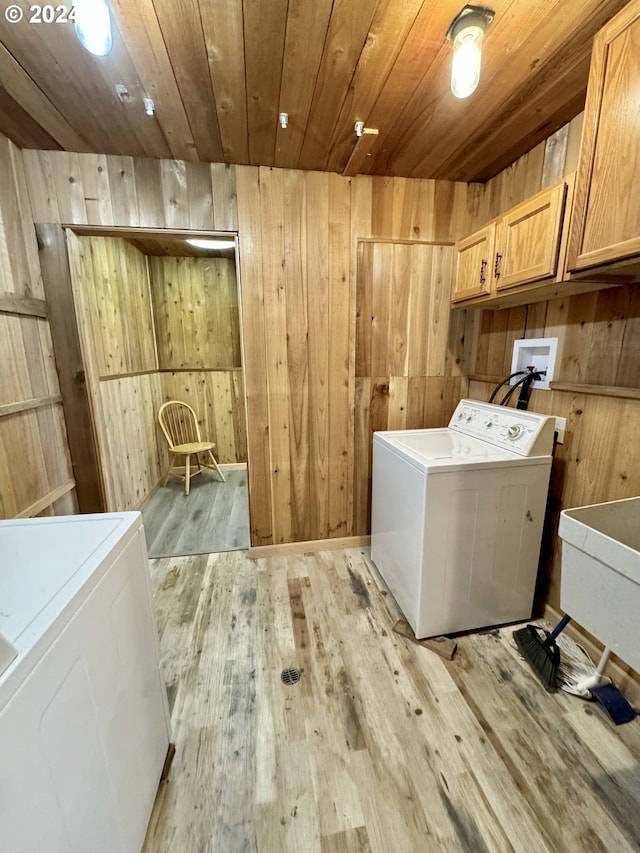 laundry area with cabinets, light hardwood / wood-style flooring, washer / clothes dryer, and wooden walls