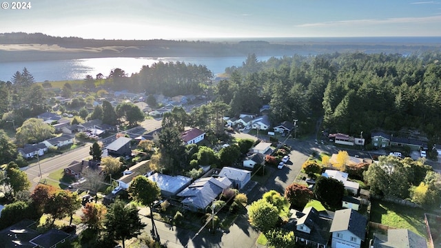aerial view of property's location featuring nearby suburban area, a large body of water, and a heavily wooded area
