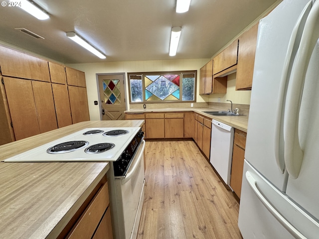 kitchen with white appliances, sink, and light hardwood / wood-style flooring