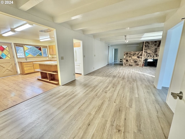 unfurnished living room featuring light wood-style flooring and beamed ceiling