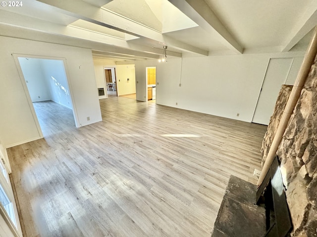 unfurnished living room featuring light hardwood / wood-style flooring and beamed ceiling