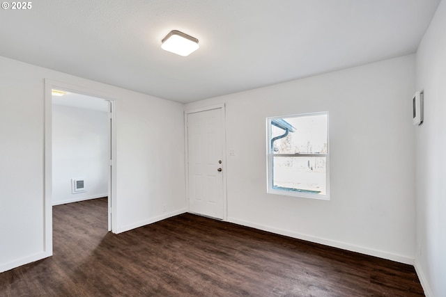 unfurnished room with dark wood-type flooring