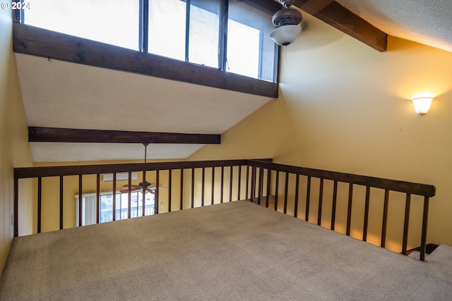 interior space featuring a textured ceiling, vaulted ceiling with beams, and carpet flooring