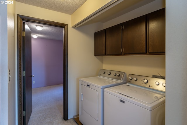 washroom with light carpet, cabinets, a textured ceiling, and washer and clothes dryer