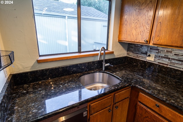 kitchen featuring decorative backsplash, dark stone counters, sink, and stainless steel dishwasher