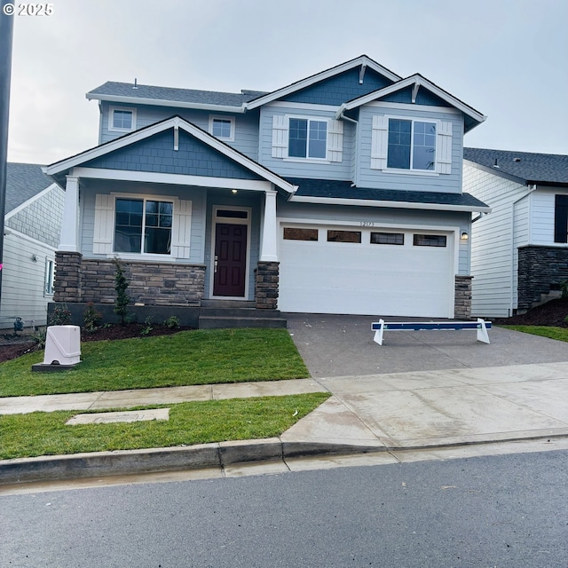 craftsman inspired home featuring a garage and a front lawn