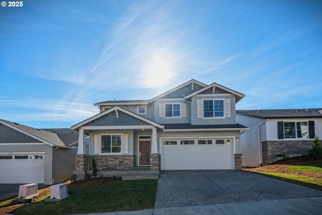 craftsman-style home with an attached garage, driveway, and stone siding