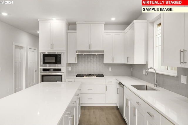 kitchen featuring stainless steel appliances, light countertops, white cabinetry, and a sink