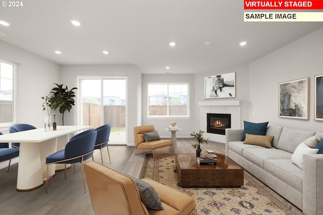 living room with light wood-style floors, baseboards, a tiled fireplace, and recessed lighting