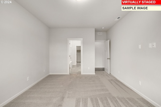 unfurnished bedroom with carpet floors, a walk in closet, visible vents, and baseboards