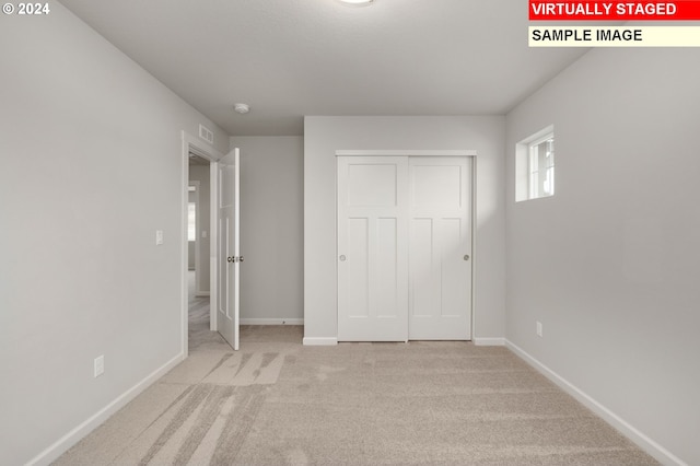 unfurnished bedroom with a closet, carpet flooring, visible vents, and baseboards