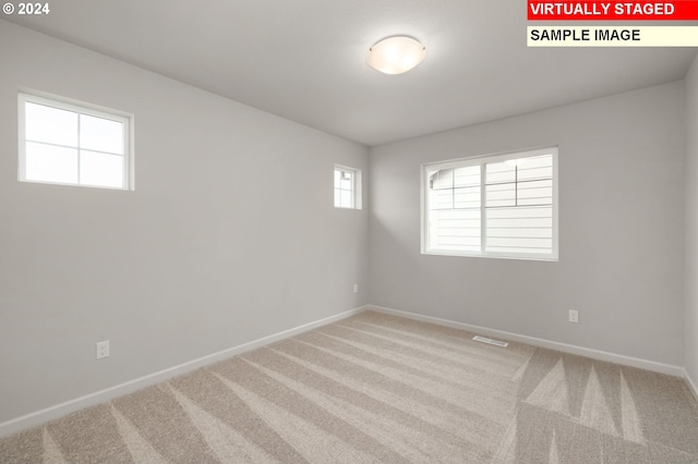 empty room with carpet floors, visible vents, and baseboards