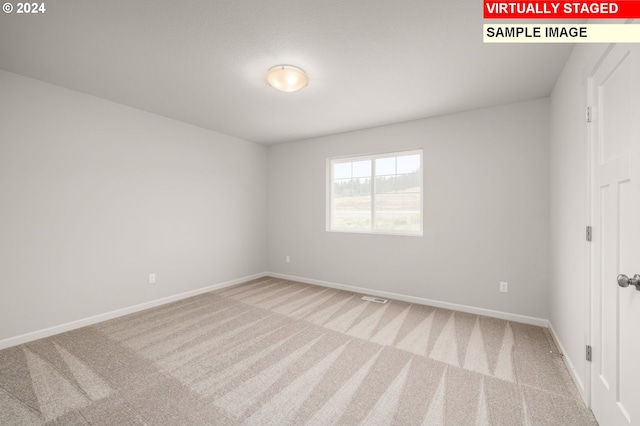 carpeted spare room with visible vents and baseboards