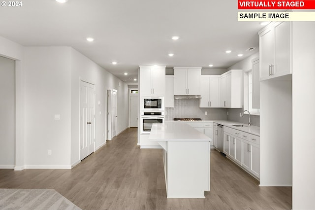 kitchen featuring stainless steel appliances, light wood-type flooring, light countertops, and a sink